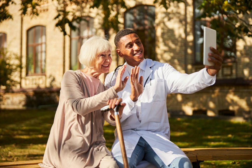 Happy physician and old woman taking a photo