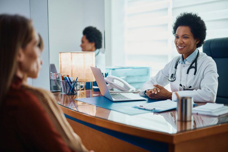 Happy black pediatrician communicating with mother and child at her office.