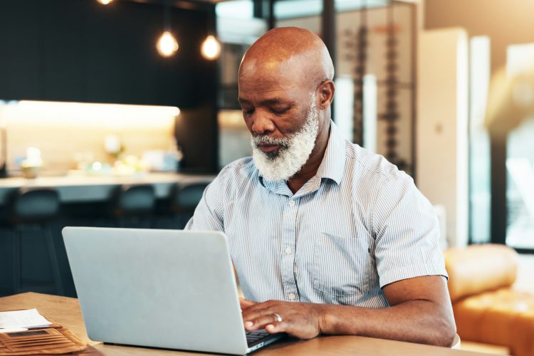 Senior black man, documents and laptop in home for immigration, typing or compliance for internatio