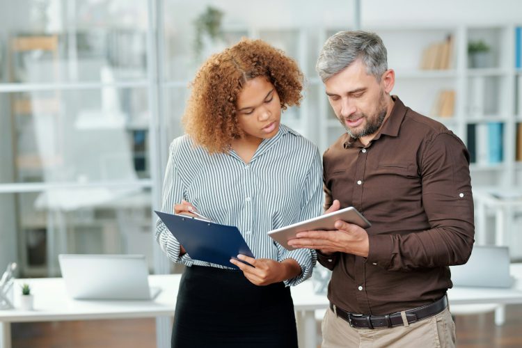 Two contemporary bankers checking financial data on paper and in tablet