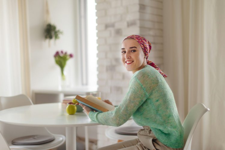 Young woman with cancer reading book, cancer awareness concept.